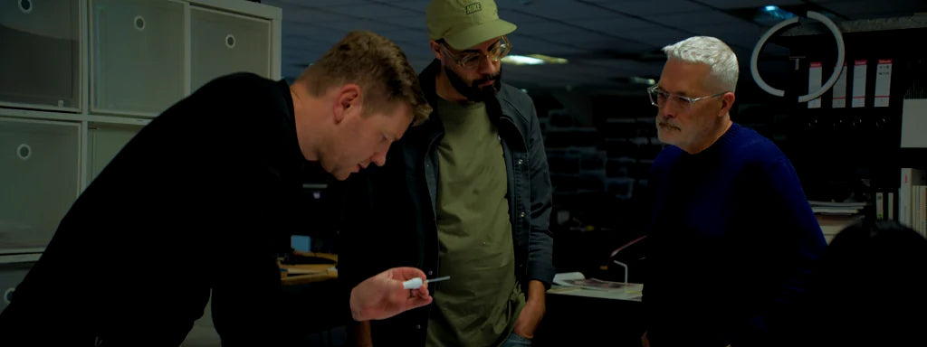 Three collaborators examining a sample in a workshop.